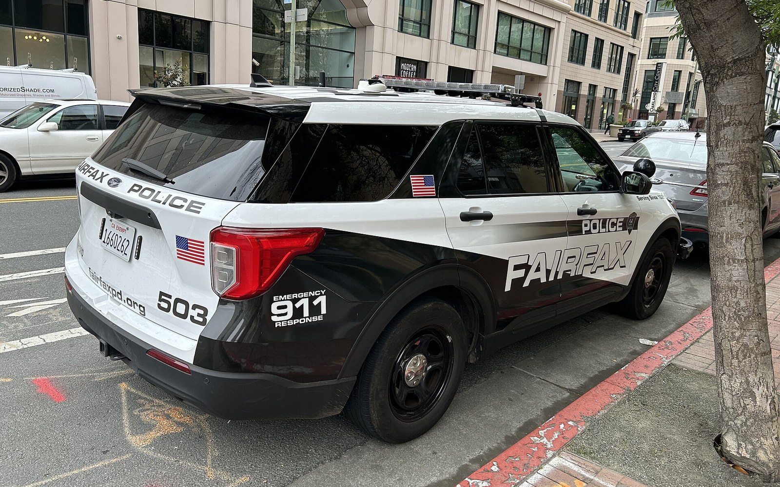A Fairfax police SUV parked along a city street beside other vehicles